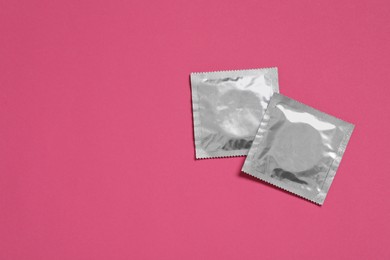 Photo of Condom packages on pink background, flat lay and space for text. Safe sex