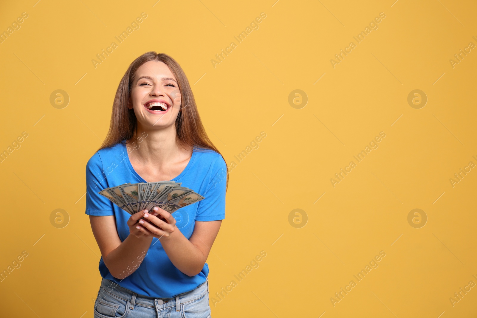 Photo of Portrait of happy lottery winner with money on yellow background, space for text