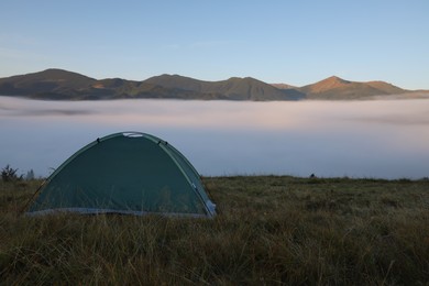 Photo of Picturesque mountain landscape with camping tent in foggy morning. Space for text