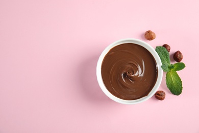 Photo of Dessert bowl with sweet chocolate cream, hazelnuts and mint on color background, top view. Space for text