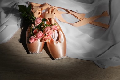 Ballet shoes. Elegant pointes and bouquet of roses on wooden floor