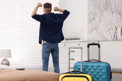 Photo of Guest stretching in stylish hotel room, focus on suitcases