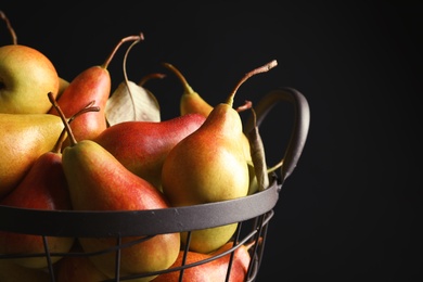 Photo of Basket with ripe pears on black background, closeup. Space for text