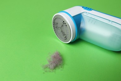 Photo of Modern fabric shaver and lint on green background