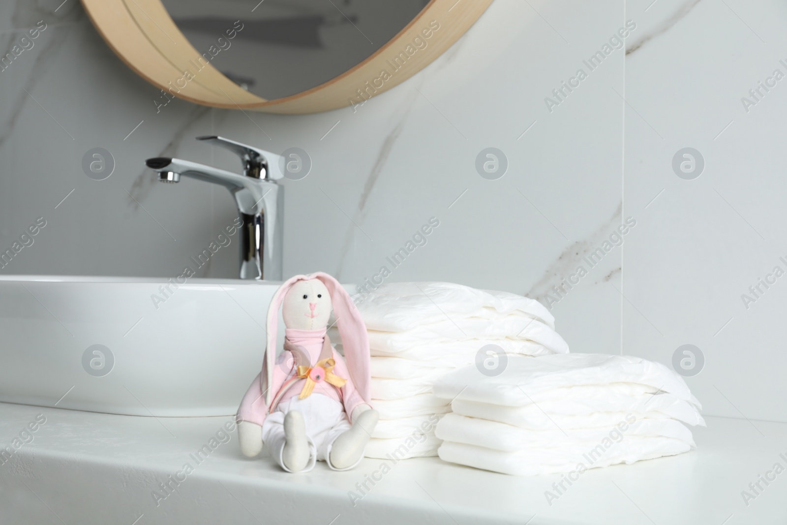 Photo of Stacks of baby diapers and toy bunny on counter in bathroom