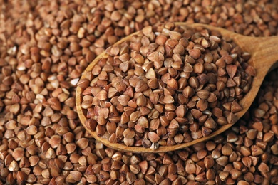 Pile of uncooked buckwheat with spoon, closeup