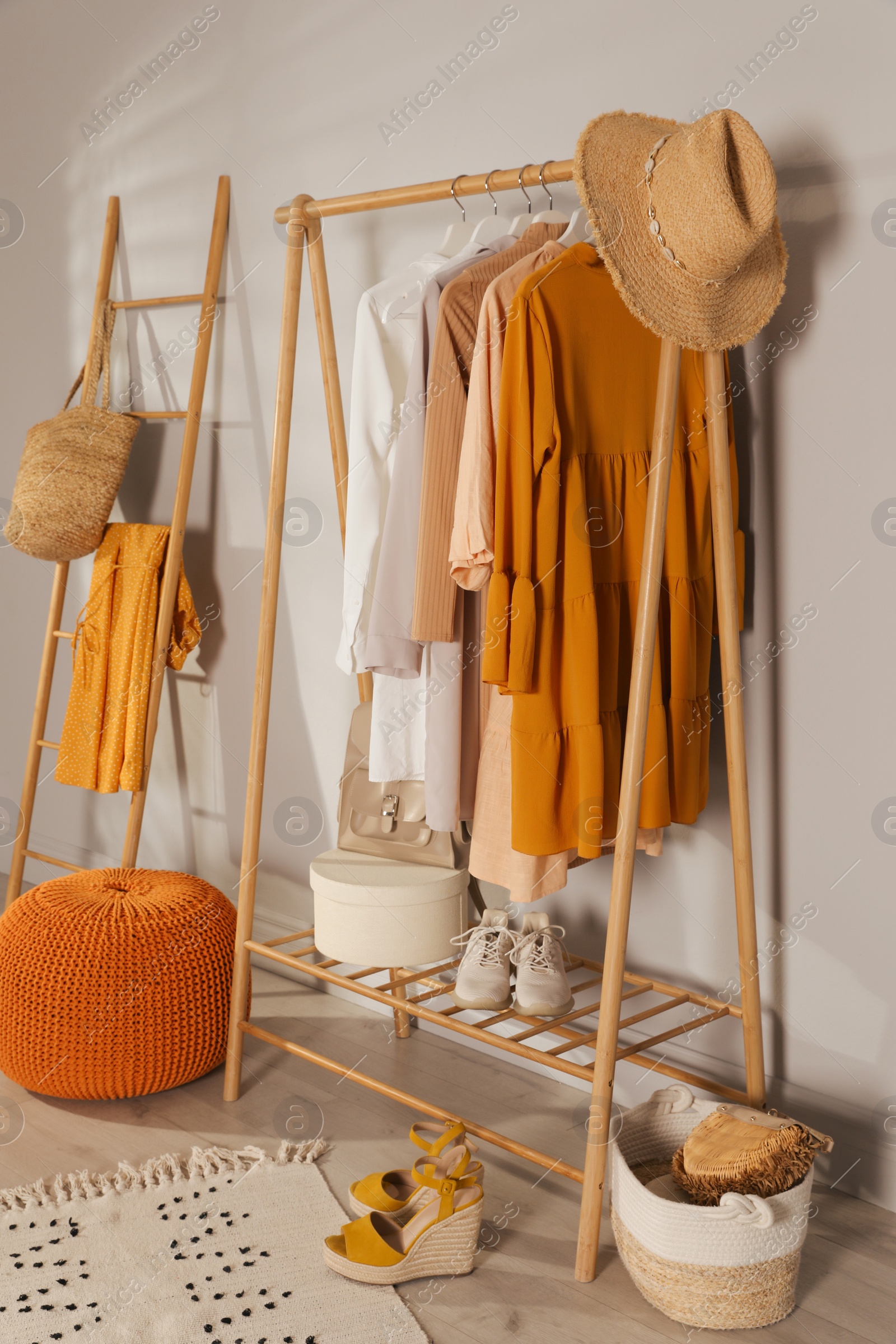 Photo of Modern dressing room interior with stylish clothes, shoes and orange pouf