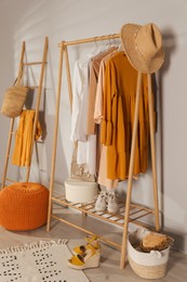 Modern dressing room interior with stylish clothes, shoes and orange pouf