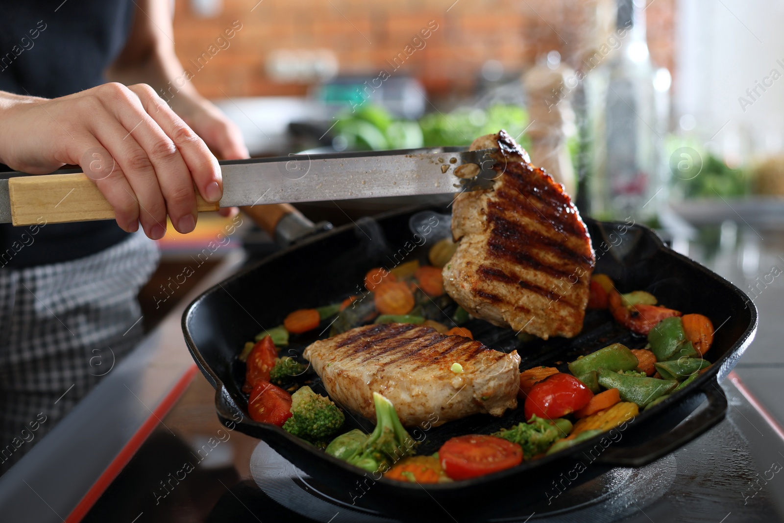 Photo of Professional chef cooking meat on stove in restaurant kitchen, closeup