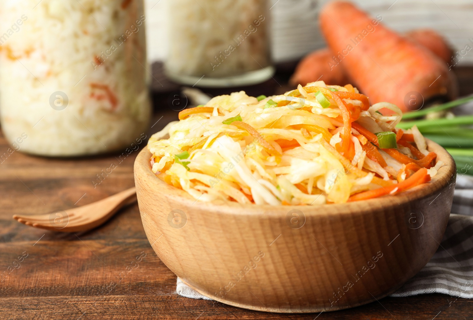 Photo of Tasty fermented cabbage on wooden table, closeup