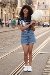 Photo of Happy woman with cotton candy on city street