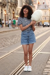 Happy woman with cotton candy on city street