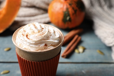 Photo of Cup with tasty pumpkin spice latte on wooden table, closeup