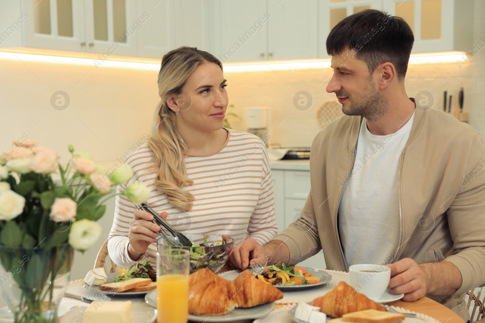 Photo of Happy couple having breakfast together at table in kitchen