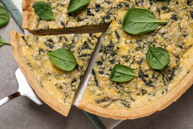 Photo of Delicious homemade spinach pie and spatula on grey table, top view