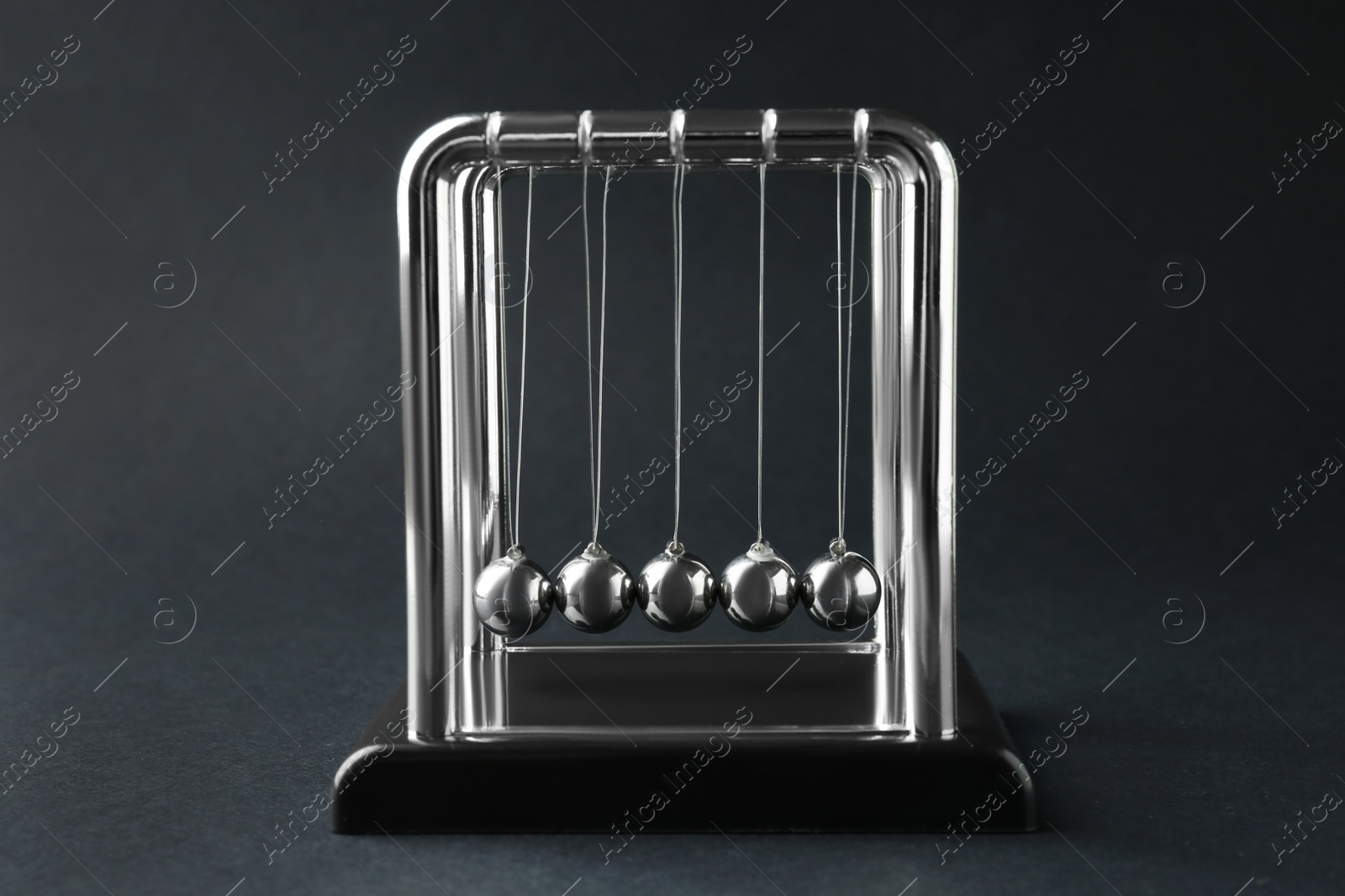 Photo of Newton's cradle on dark background. Physics law of energy conservation