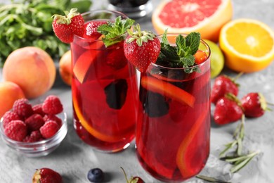 Delicious refreshing sangria with fresh fruits and berries on light grey table, closeup