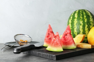 Photo of Watermelon and melon slices on cutting board against light background