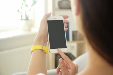 Photo of Young woman holding mobile phone with blank screen in hand indoors