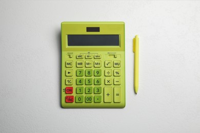 Calculator and pen on white table, top view