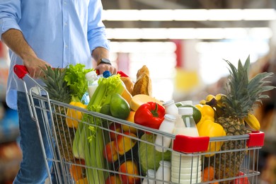 Image of Man with shopping cart full of groceries in supermarket, closeup
