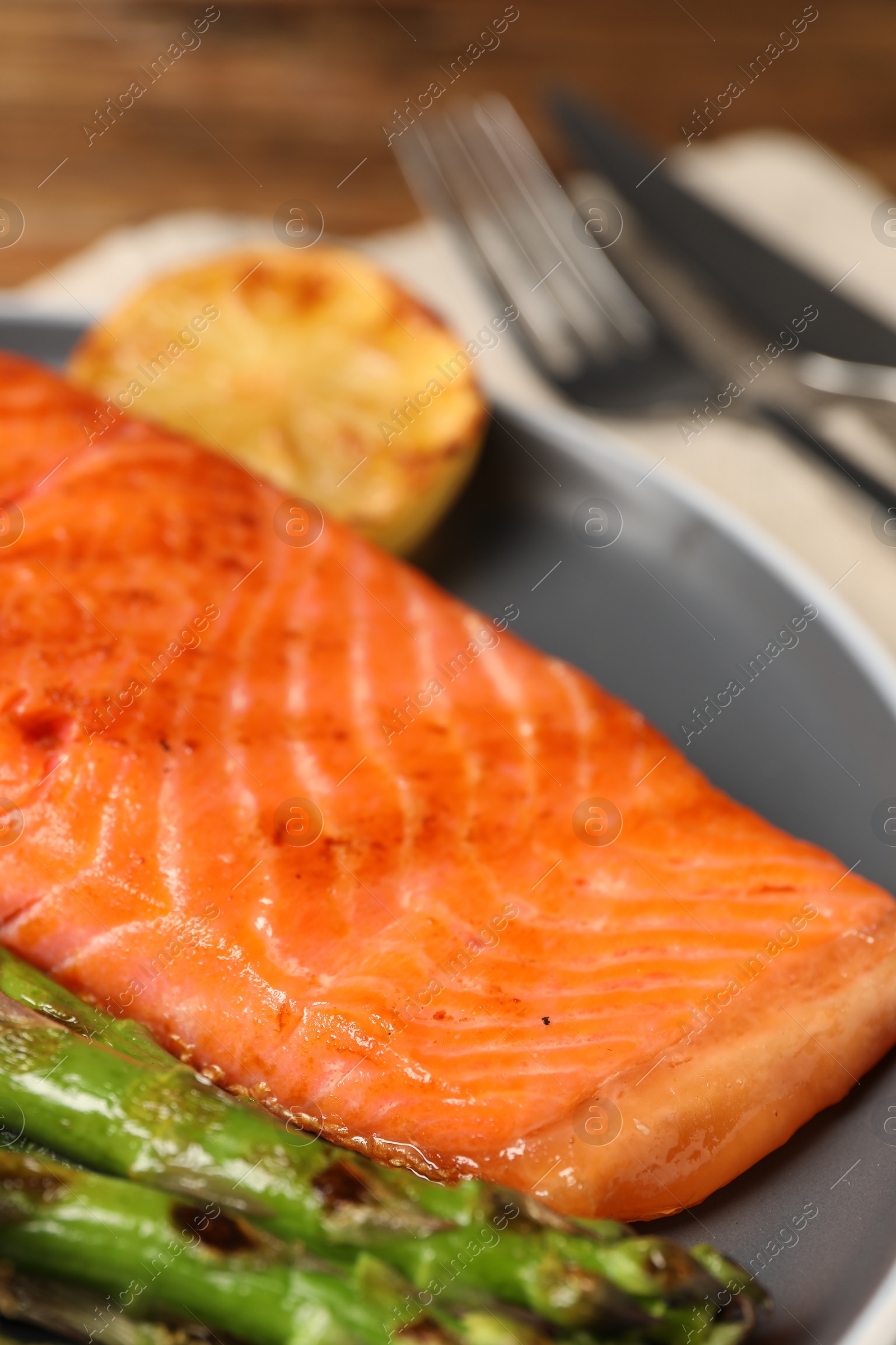 Photo of Tasty grilled salmon with asparagus and lemon served on plate, closeup