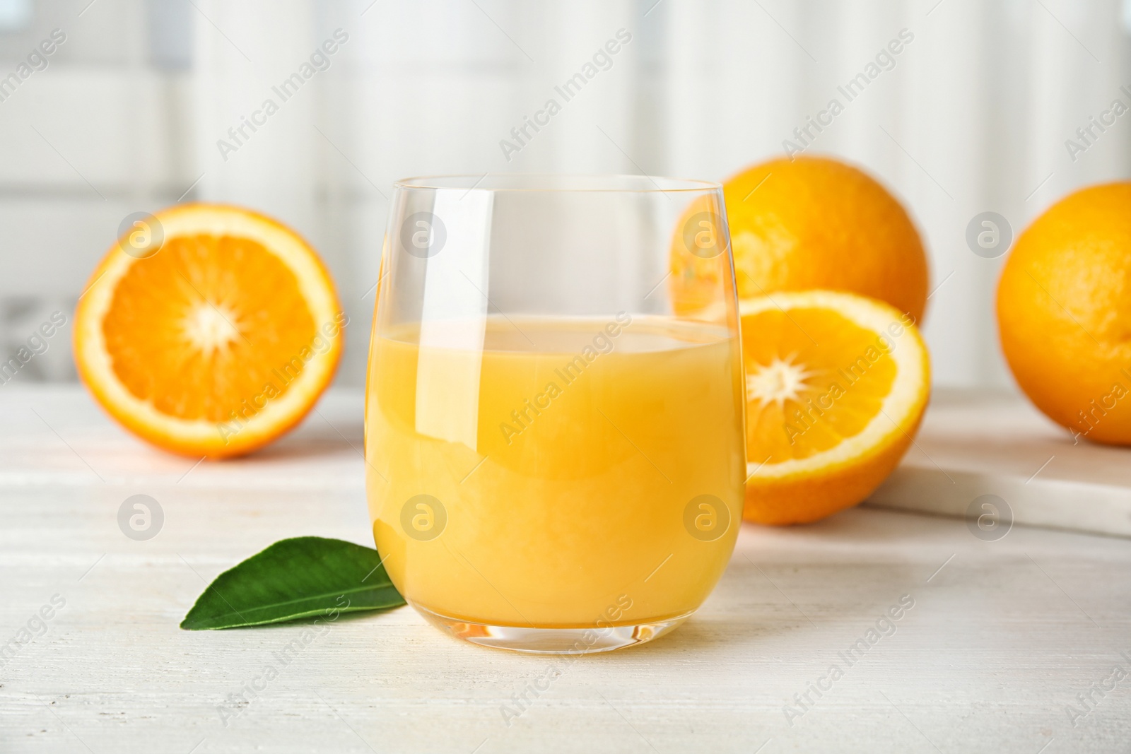 Photo of Glass with orange juice and fresh fruit on table