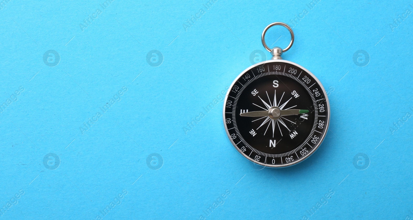 Photo of One compass on light blue background, top view. Space for text