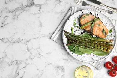 Tasty salmon steak served with grilled asparagus on white marble table, flat lay. Space for text