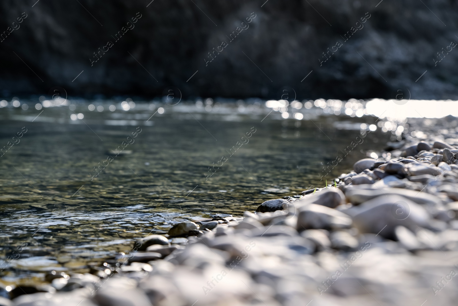 Photo of River coast with stones and pebbles on sunny day