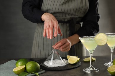 Woman making delicious Margarita cocktail at grey table, closeup