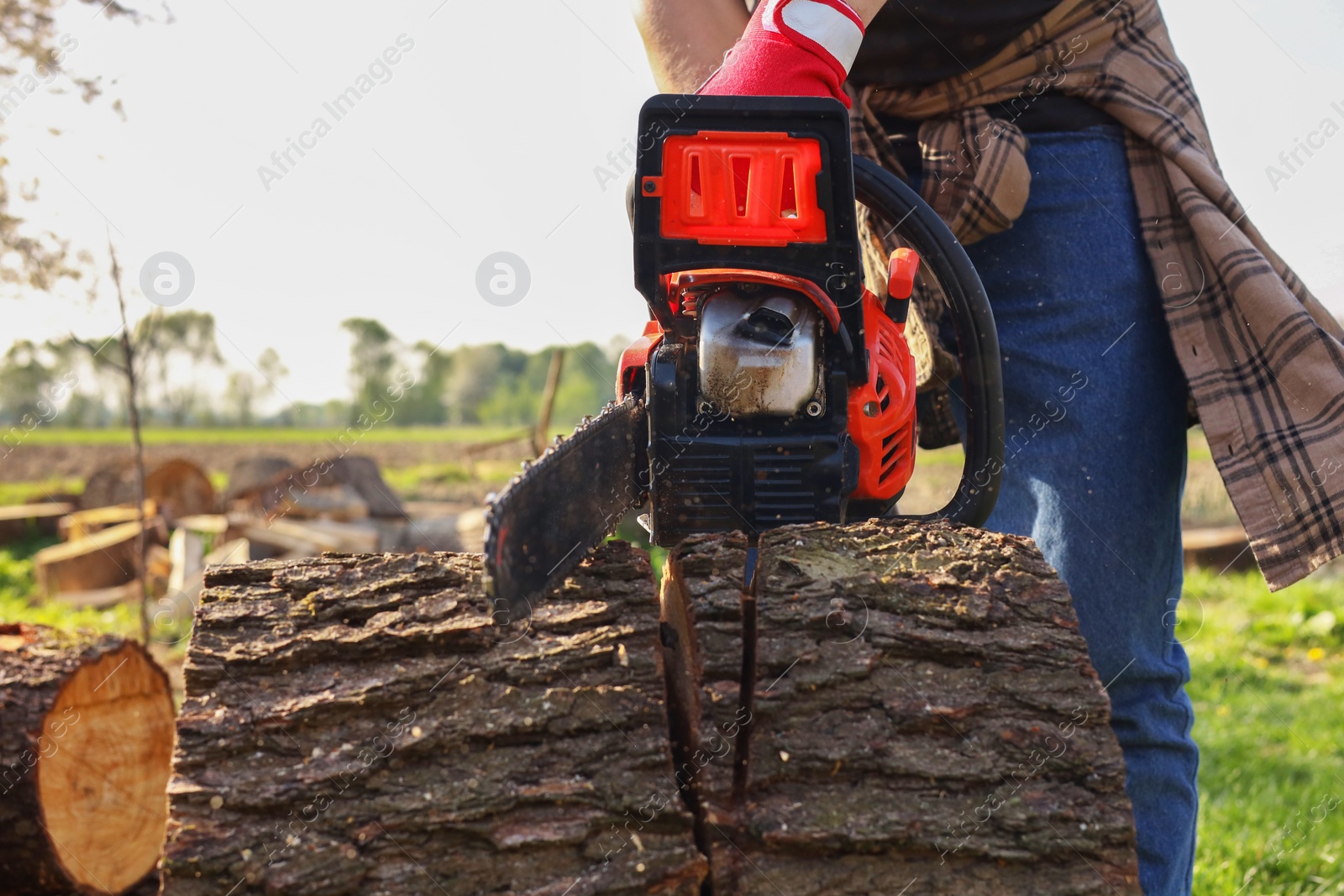 Photo of Man sawing wooden log outdoors, closeup view