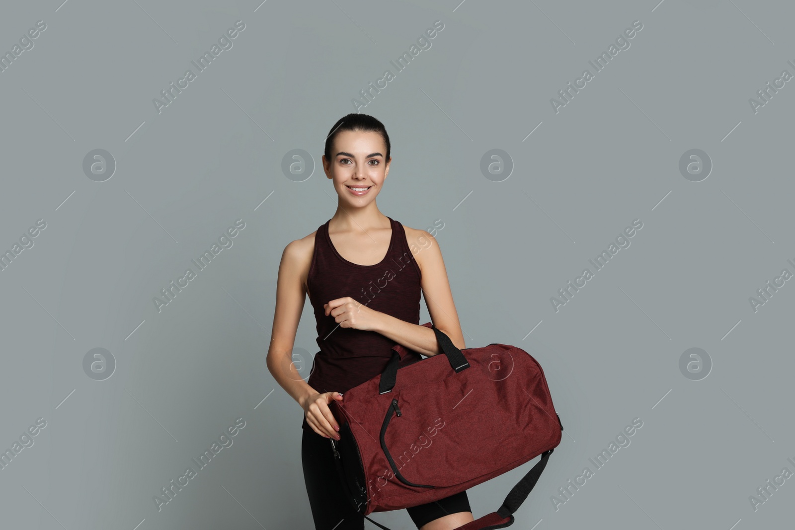 Photo of Beautiful woman with sports bag on grey background