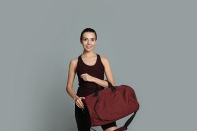 Beautiful woman with sports bag on grey background