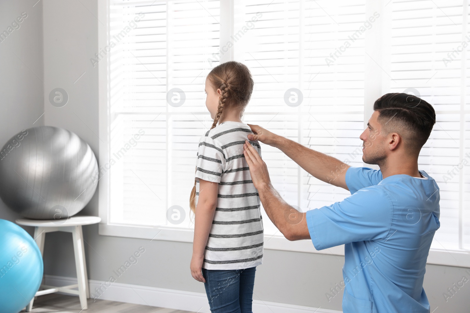 Photo of Orthopedist examining child's back in clinic. Scoliosis treatment