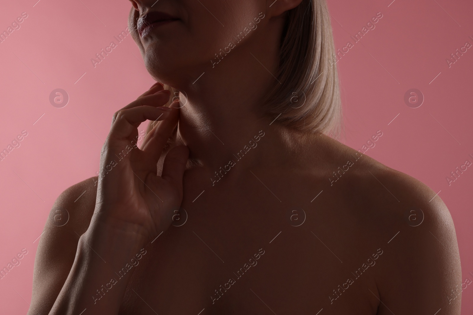 Photo of Woman touching her neck on pink background, closeup