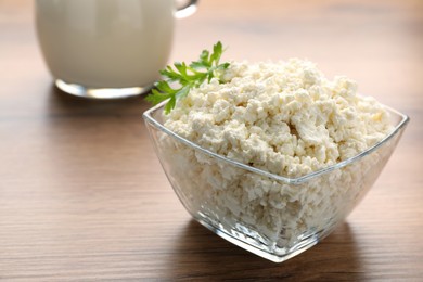 Delicious fresh cottage cheese with parsley on wooden table, closeup
