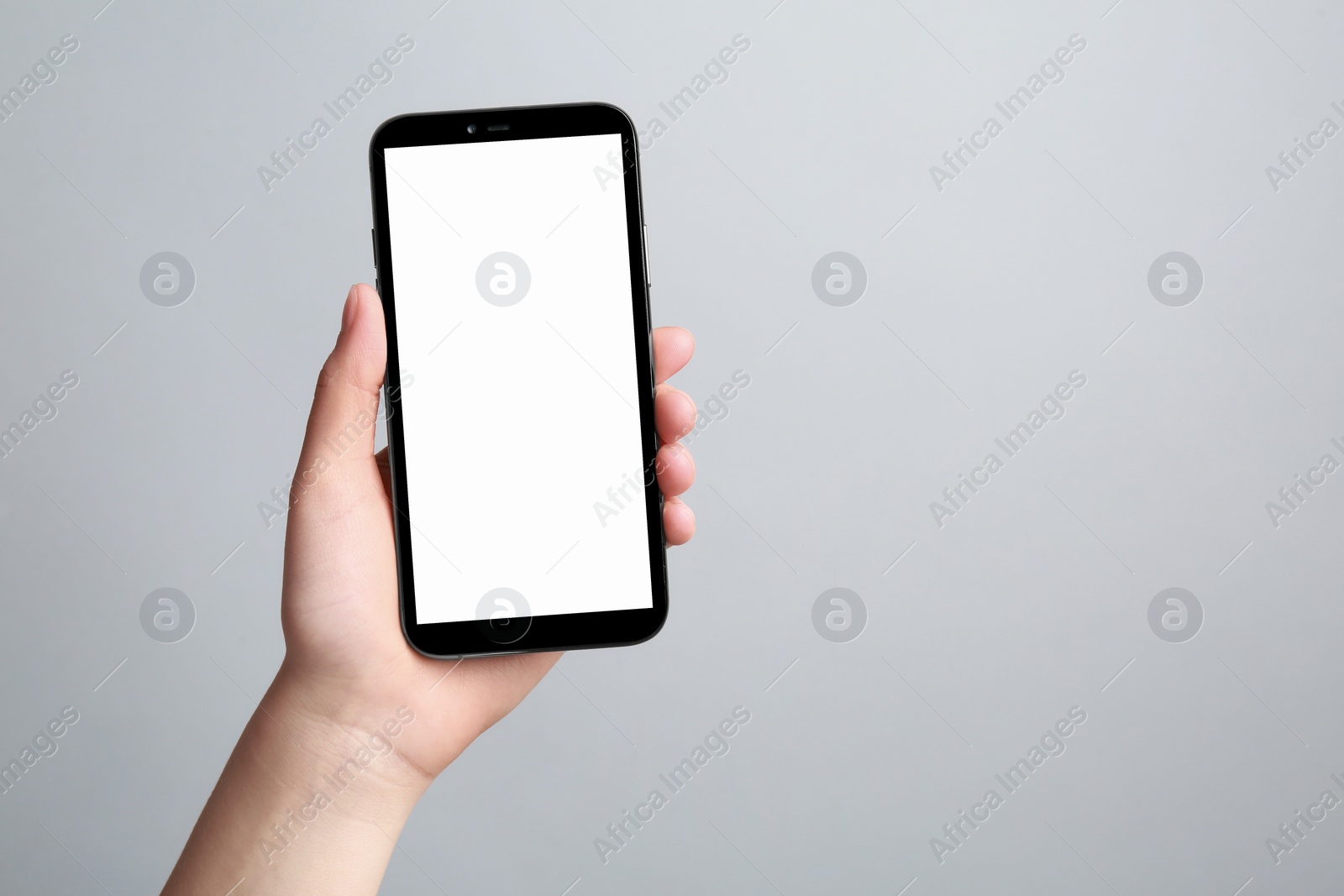 Photo of Woman holding smartphone with blank screen on grey background, closeup. Mockup for design