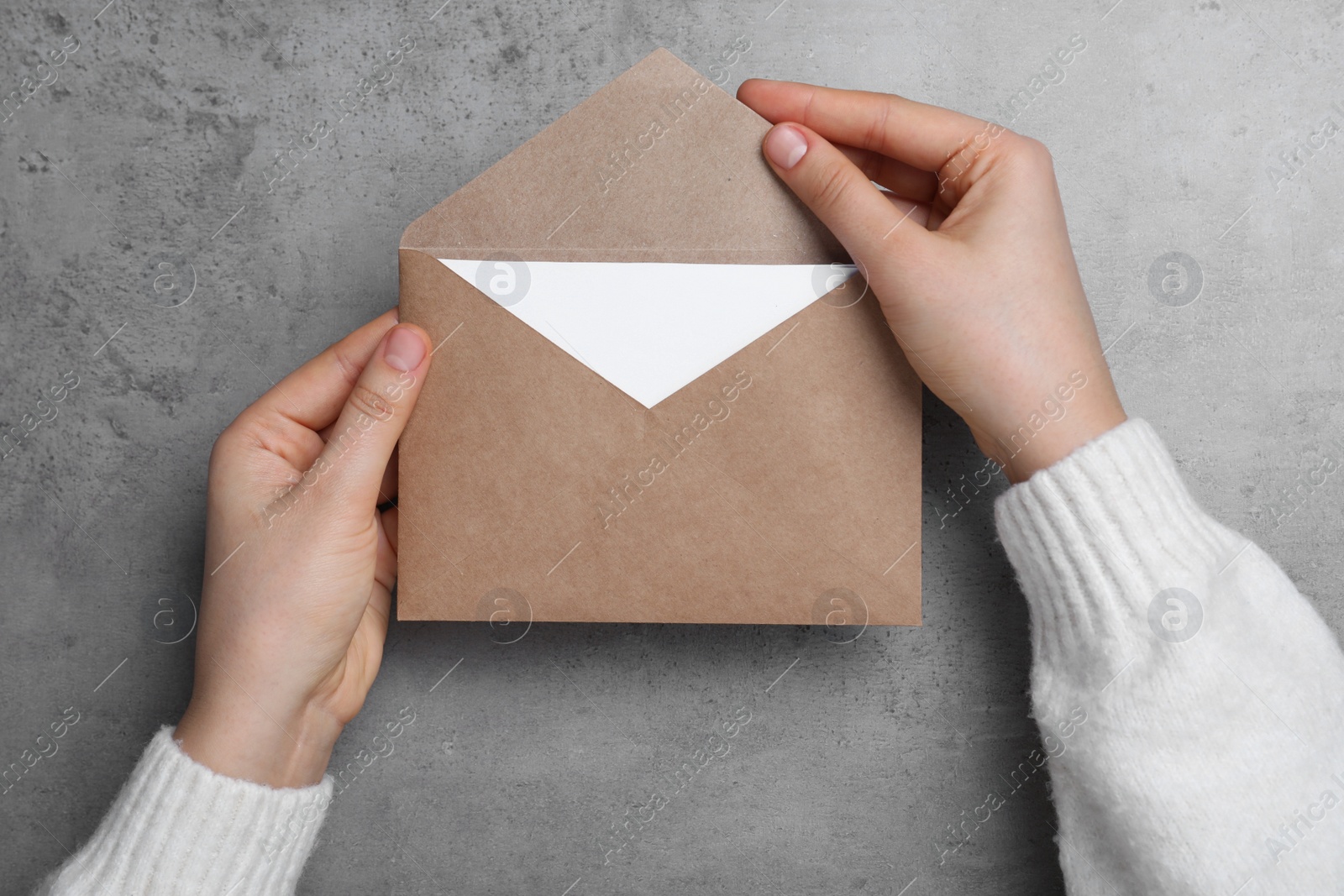 Photo of Woman with brown envelope at grey table, top view