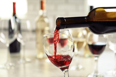 Photo of Pouring delicious red wine into glass on table
