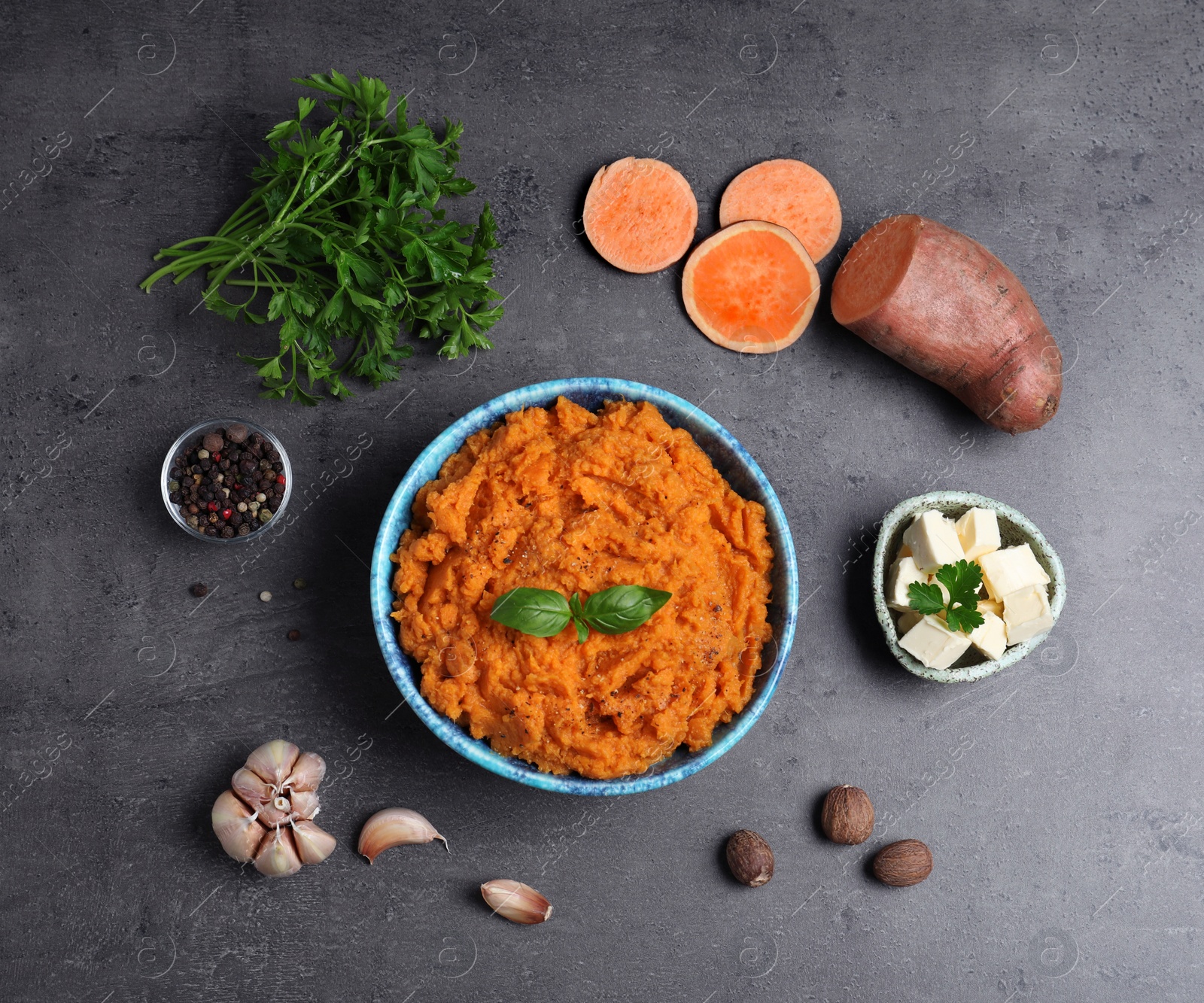 Photo of Flat lay composition with bowl of sweet potato puree and ingredients on grey table