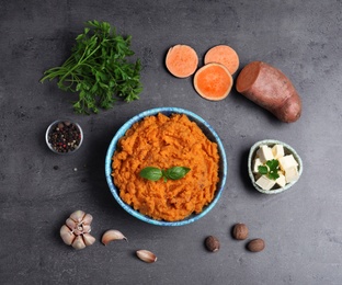 Flat lay composition with bowl of sweet potato puree and ingredients on grey table