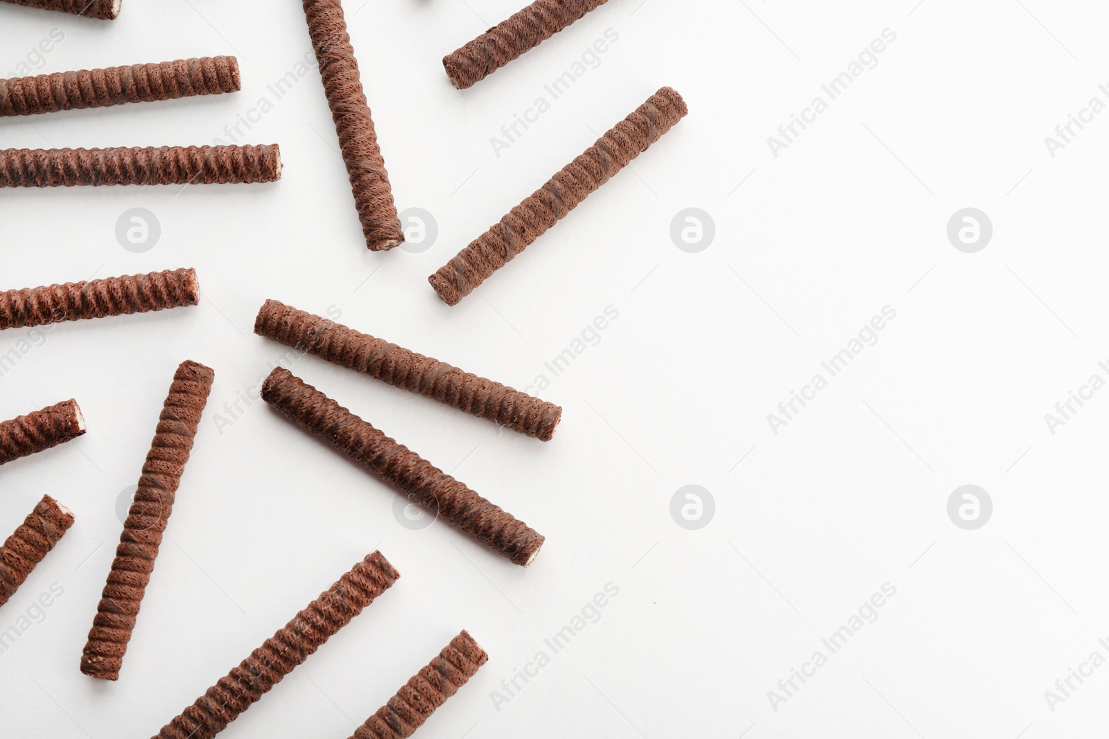 Photo of Delicious chocolate wafer rolls on white background, top view with space for text. Sweet food