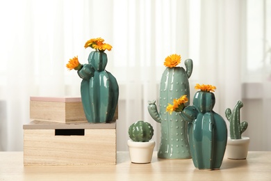 Trendy cactus shaped vases on table near window. Creative decor