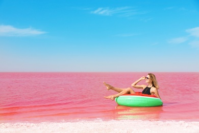 Beautiful woman on inflatable ring in pink lake