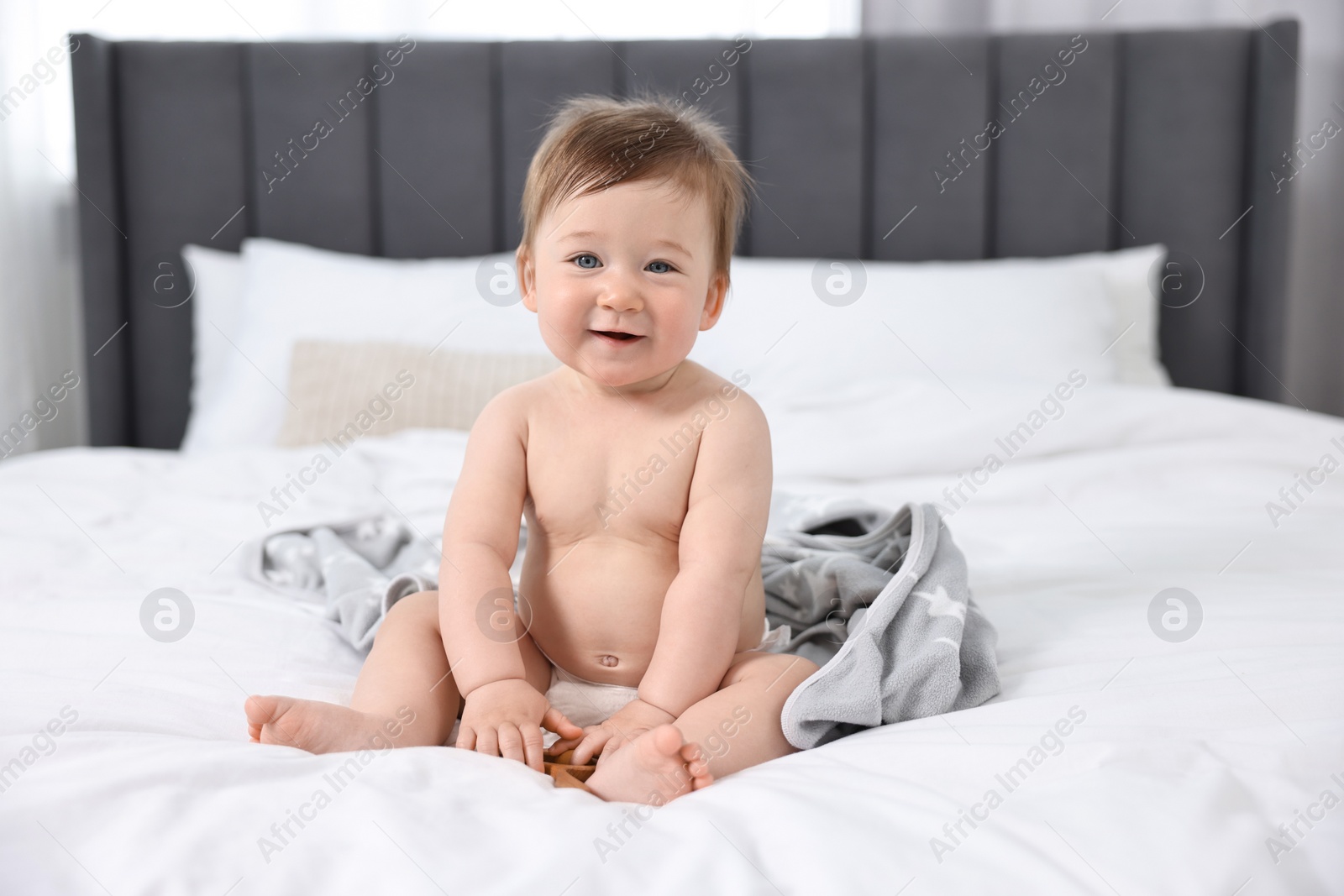 Photo of Cute baby boy sitting on bed at home