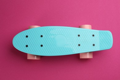 Photo of Turquoise skateboard on crimson background, top view
