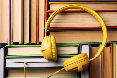 Modern headphones on stack of books, top view