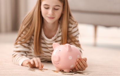 Photo of Teen girl with piggy bank and money at home