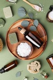 Flat lay composition with different spa products and eucalyptus branches on olive background